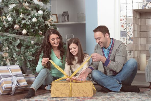 Smiling family unpacking presents with the Christmas tree in the background