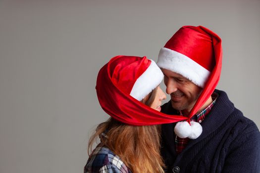 Happy smiling couple in Santa hats on gray background