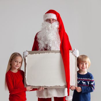 Santa Claus with children holding vintage paper billboard with copy space for text