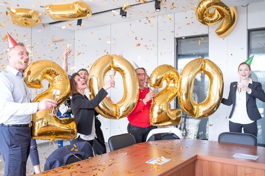 Business people are celebrating holiday in modern office drinking champagne and having fun in coworking. Merry Christmas and Happy New Year 2020 concept