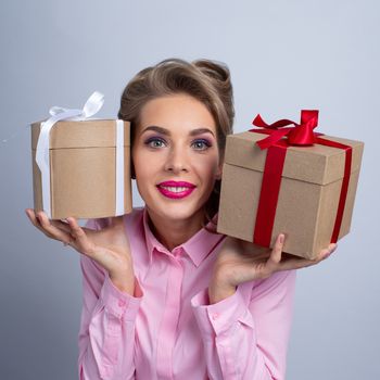 Young happy woman puts her ear to holiday presents with bows