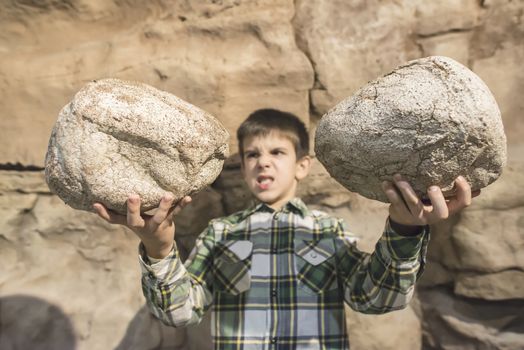 Strong child holds heavy stones. 