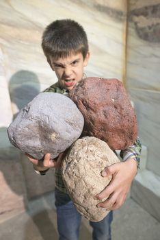 Strong child holds heavy stones. 