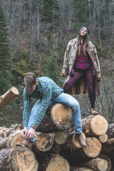 Young woman and men on wood logs in the forest