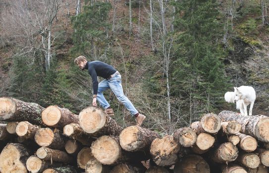 Young man and dog on logs in the forest. Fashion style