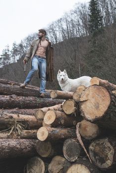 Young man and dog on logs in the forest. Fashion style