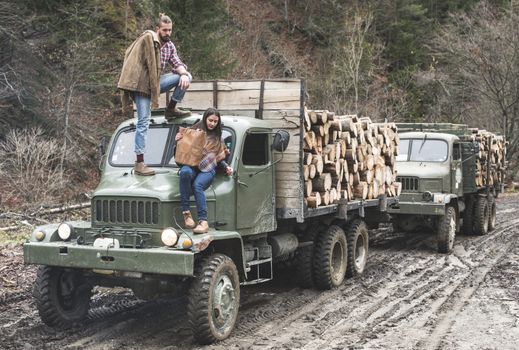 Young man and girl on truck with logs in the forest