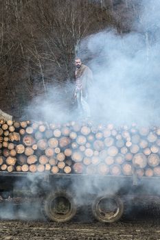 Young man on vintage truck with logs in the forest.