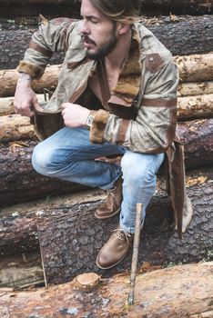 Young men on logs in the forest. Leather and jeans