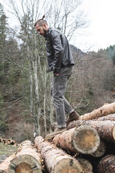 Young men on logs in the forest. Leather and jeans