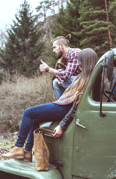 Young men and girl on vintage truck in the forest