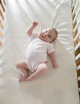 Baby in a baby bed. White clothes. Window light