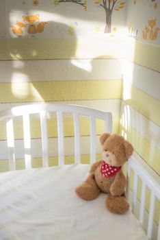 Teddy bear in a baby room. Baby and mother silhouette on the wall.