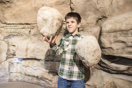 Strong child holds heavy stones. 