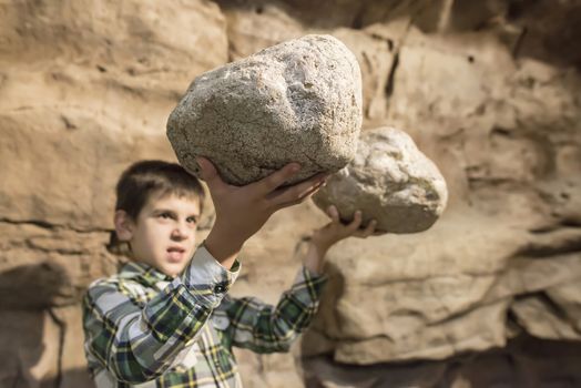 Strong child holds heavy stones. 