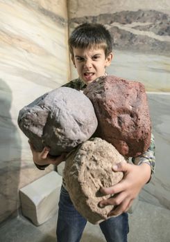 Strong child holds heavy stones. 