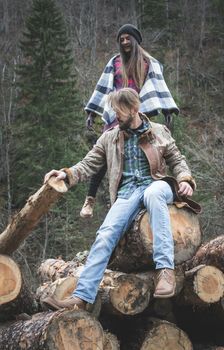 Young woman and men on wood logs in the forest