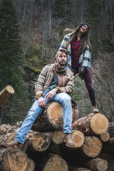 Young woman and men on wood logs in the forest