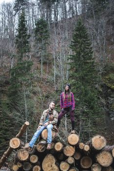 Young woman and men on wood logs in the forest