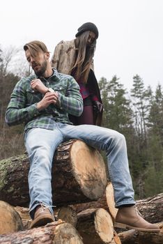 Young woman and men on wood logs in the forest