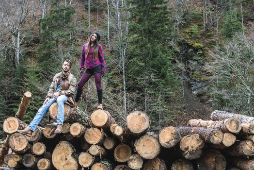 Young woman and men on wood logs in the forest