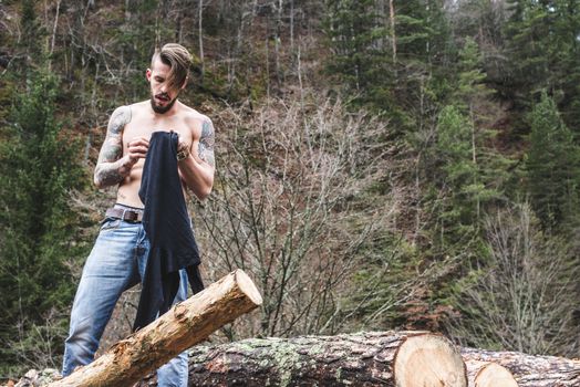 Young men on logs in the forest. Men dress.