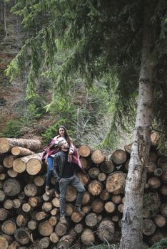 Young woman and men on wood logs in the forest