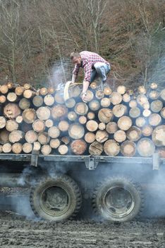 Young man on vintage truck with logs in the forest.