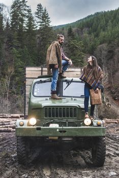 Young man and girl on truck with logs in the forest