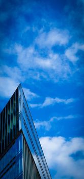 Modern Architecture. Minimal Aesthetics. Low angle view of a futuristic triangular building against a clear blue sky background. Corner building.