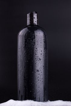 Big black hair shampoo bottle on black background