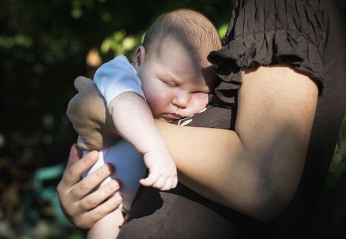 Baby in his mother's arms. Close up