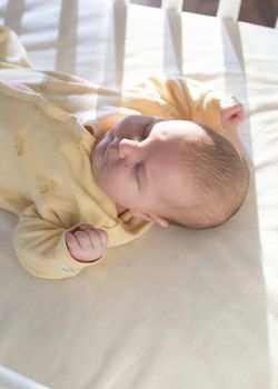 Baby in a baby bed. White clothes. Window light