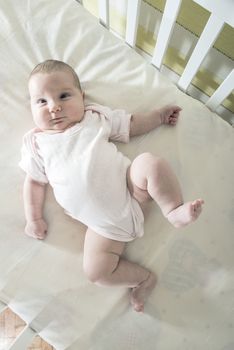 Baby in a baby bed. White clothes. Window light