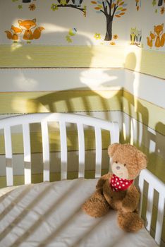 Teddy bear in a baby room. Baby and mother silhouette on the wall.