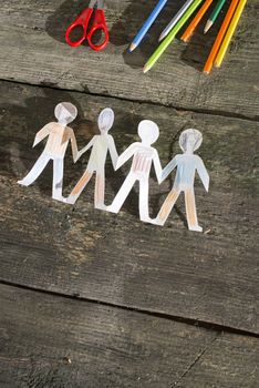 Paper made people figures. Painted white figures on wooden board