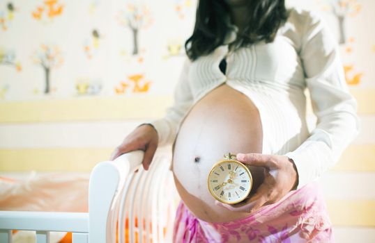 Pregnant women in a baby room. Watch
