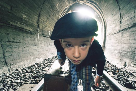 Child walking on railway road with vintage siutcase. Contra light