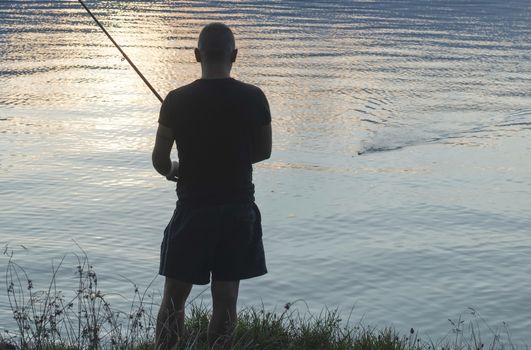 Silhouette of fisherman. Mountain dam