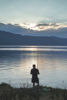 Silhouette of fisherman. Mountain dam