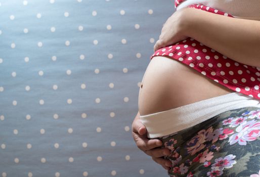 Pregnant woman shows his belly. Blue background