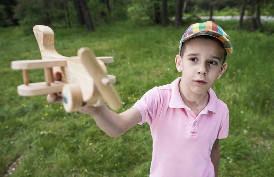 Child play with a wooden plane in the mountain. Forest