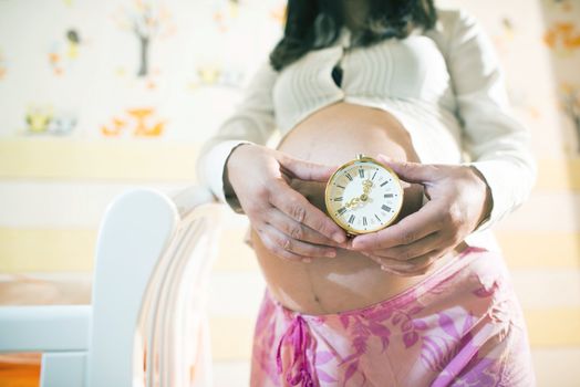 Pregnant women in a baby room. Watch