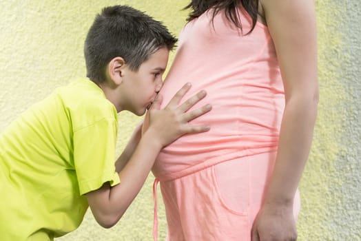 Pregnant women and small boy. Yellow wall