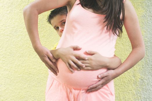 Pregnant women and small boy. Yellow wall