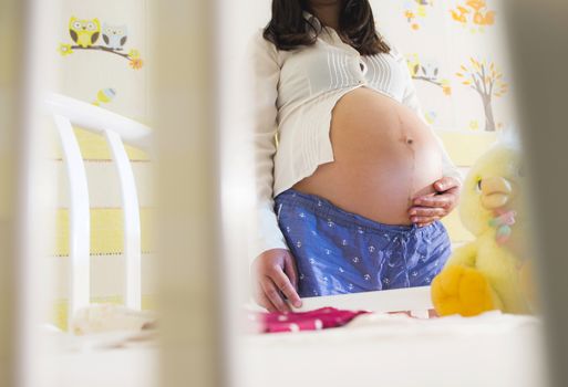 Pregnant women in a baby room. Preparing the room for the baby