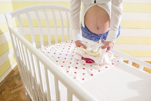 Pregnant women in a baby room. Preparing the room for the baby