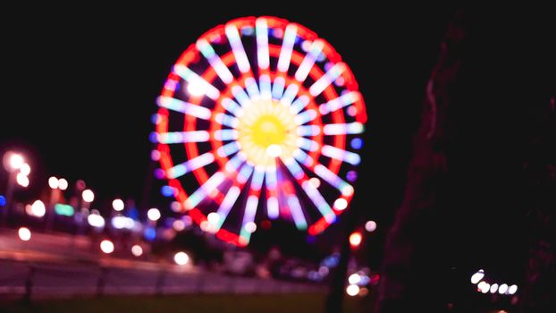 Out of focus abstract of a ferris wheel and empty road at night