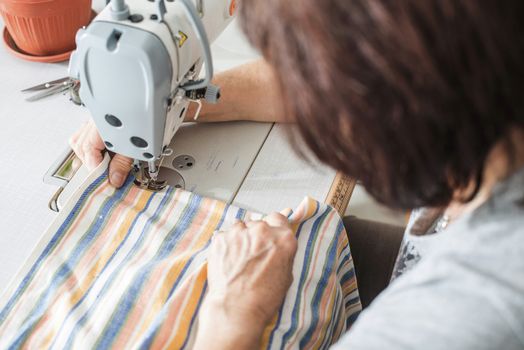 Women sew on sewing machine. White machine