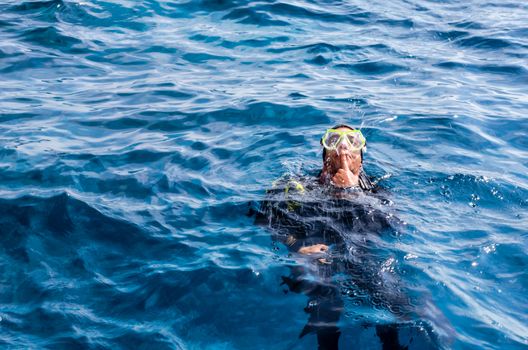 funny diving instructor entertains tourists by fountains opening from the mouth depicting a whale